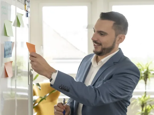 A Bosshard & Partner employee stands at the whiteboard holding a pen and a piece of paper.